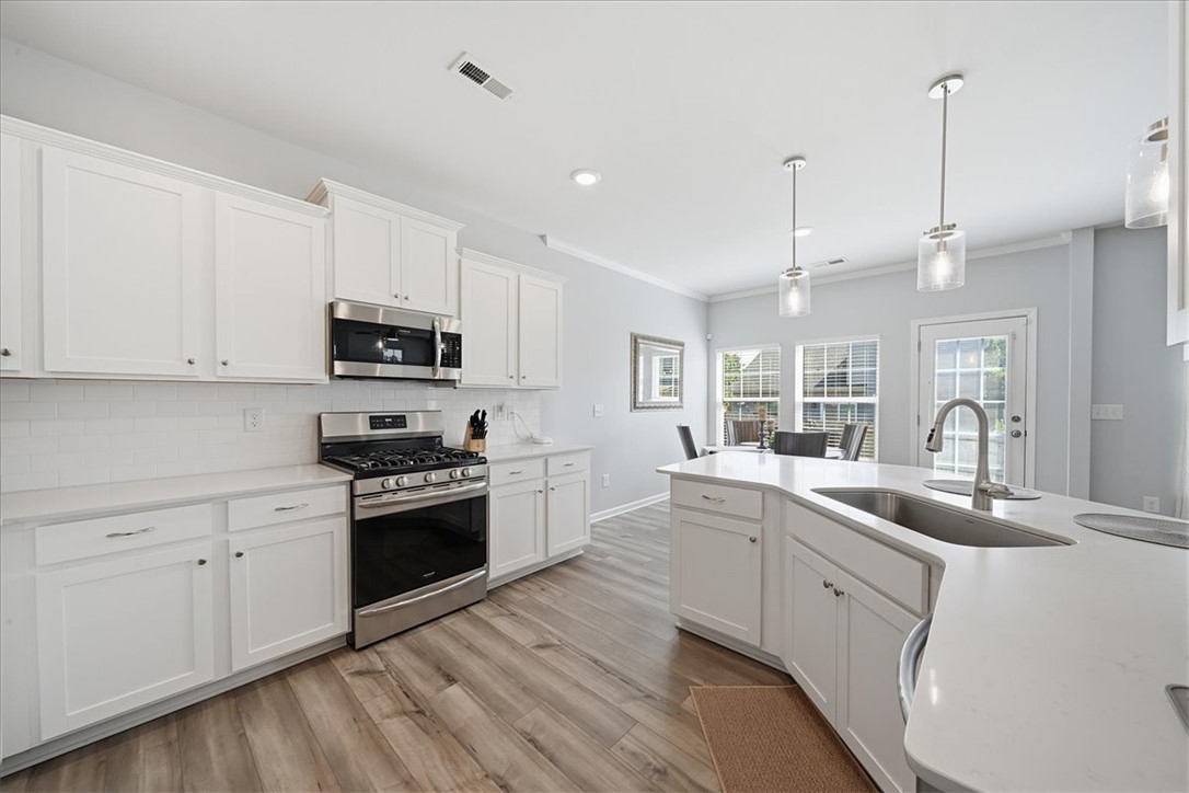 208 Grassy Creek Way Pendleton, SC 29670 - Photo 11 of 43 Modern kitchen with white cabinetry and stainless steel appliances awaits culinary adventures.