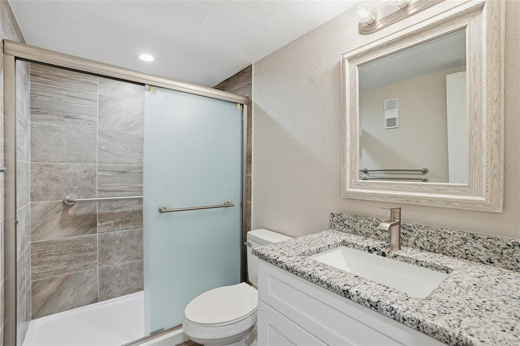 22375 Edgewater Drive, Unit 124 Punta Gorda, FL 33980 - Photo 13 of 29 a bathroom with a granite countertop sink toilet and shower