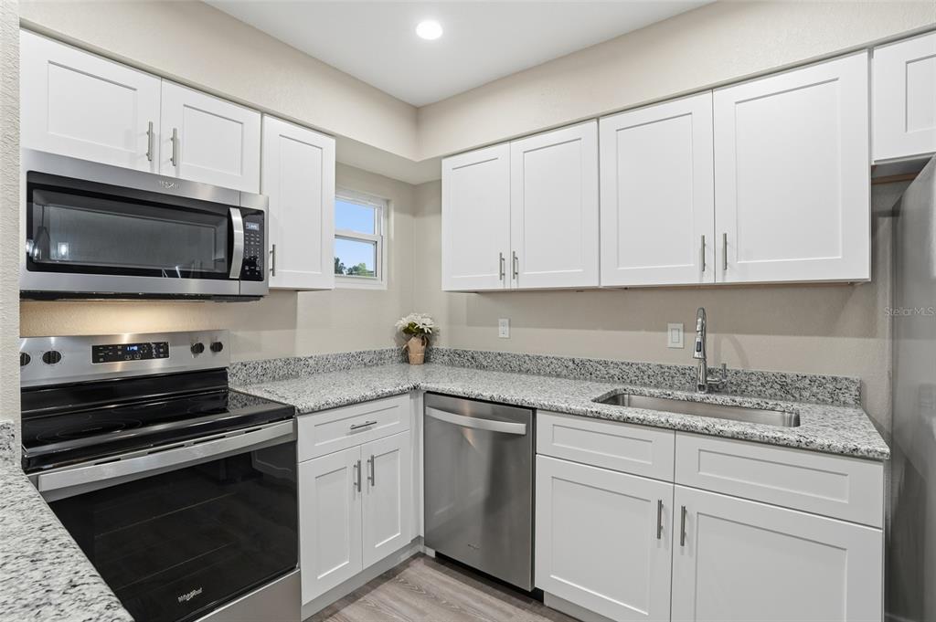 22375 Edgewater Drive, Unit 124 Punta Gorda, FL 33980 - Photo 3 of 29 a kitchen with granite countertop white cabinets and stainless steel appliances