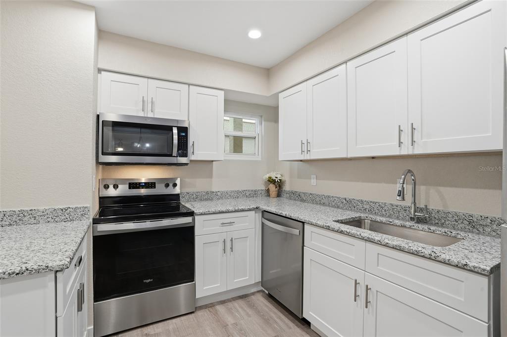 22375 Edgewater Drive, Unit 124 Punta Gorda, FL 33980 - Photo 4 of 29 a kitchen with granite countertop white cabinets white stainless steel appliances and a sink