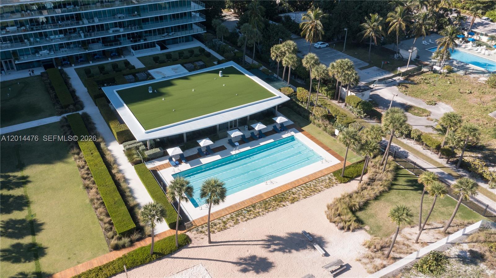 360 Ocean Drive, Unit 1106S Key Biscayne, FL 33149 - Photo 43 of 67 Aerial Amenity View – This elevated angle showcases the lap pool, landscaped lawns, beach pathway, and amenity areas adjacent to the building. The layout offers a clear look at the property’s outdoor spaces and direct access toward the shoreline.
