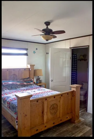 a view of an empty room with wooden floor and a ceiling fan