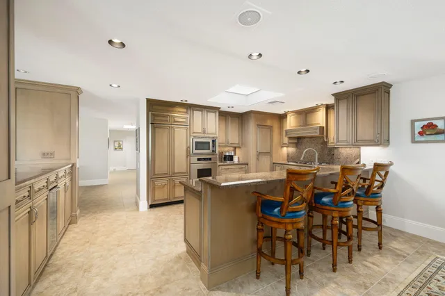 a kitchen with stainless steel appliances a table chairs refrigerator and cabinets