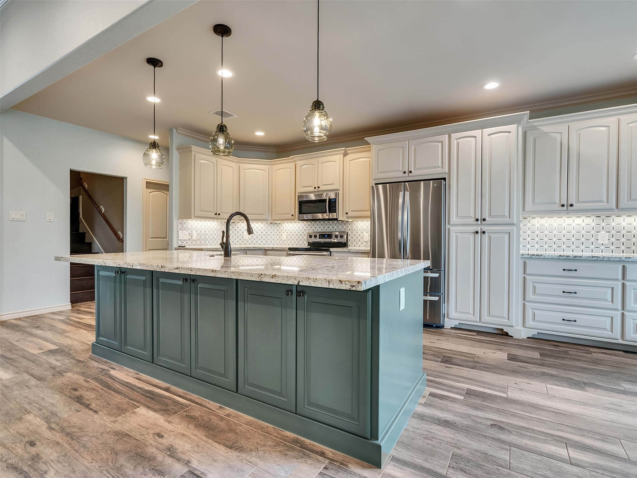 18005 Cindy Lane Conroe, TX 77302 - Photo 14 of 49 This modern kitchen features a large island with granite countertops, elegant pendant lighting, and ample cabinetry. Stainless steel appliances and a stylish backsplash add to its contemporary appeal, complemented tile with a wood feel.