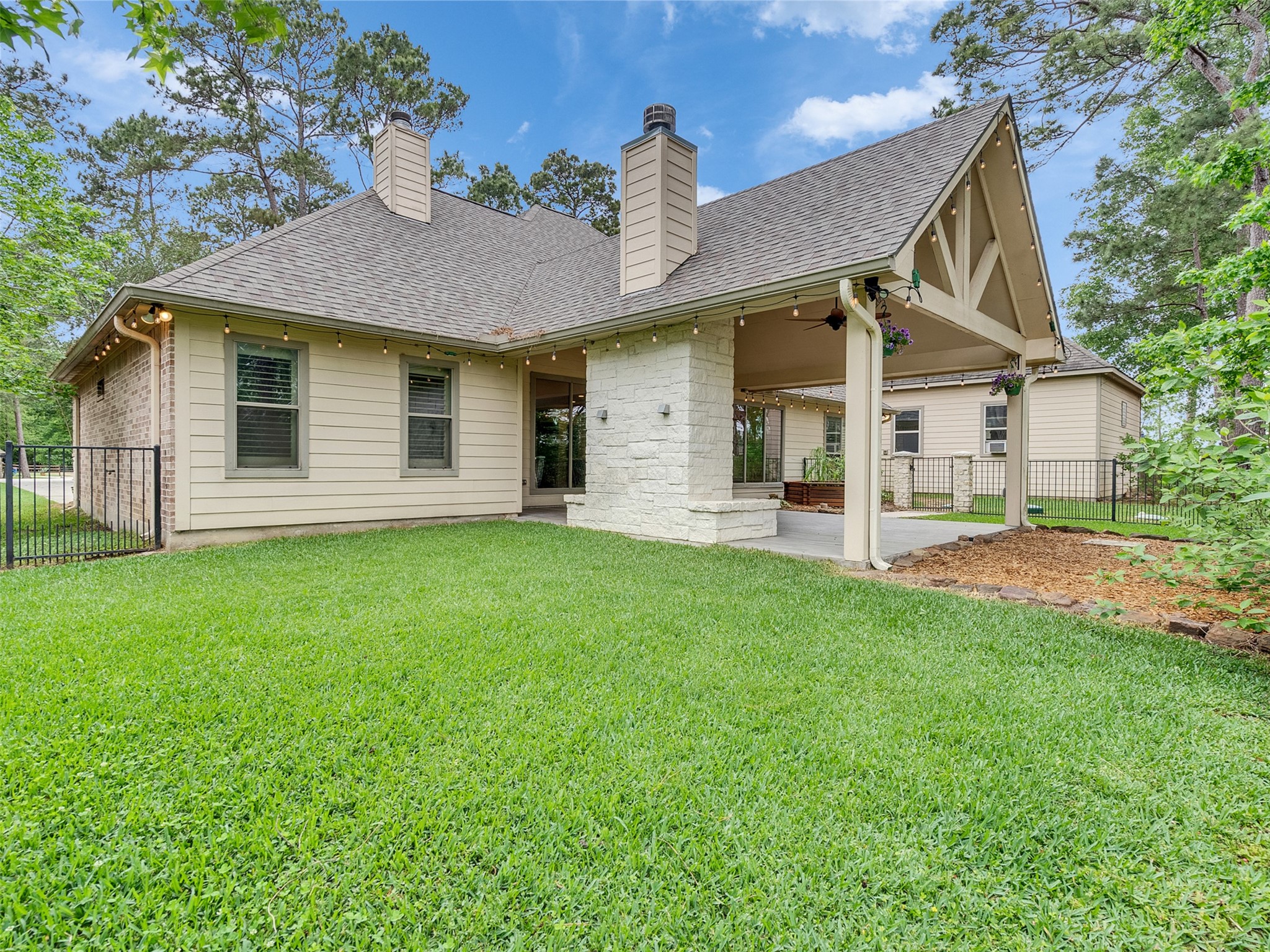 18005 Cindy Lane Conroe, TX 77302 - Photo 41 of 49 Charming home with a spacious, well-maintained backyard. Features a covered patio with a stone fireplace, perfect for outdoor gatherings. Surrounded by lush greenery for added privacy and tranquility.