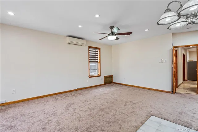 an empty room with chandelier fan and windows