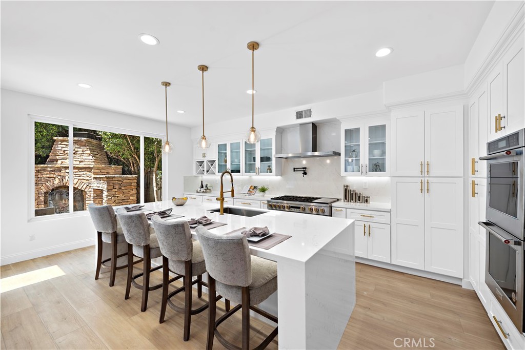 a kitchen with stainless steel appliances a dining table chairs stove refrigerator and cabinets