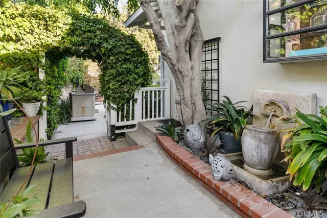 a view of a patio with couches table and chairs under an umbrella with a garden