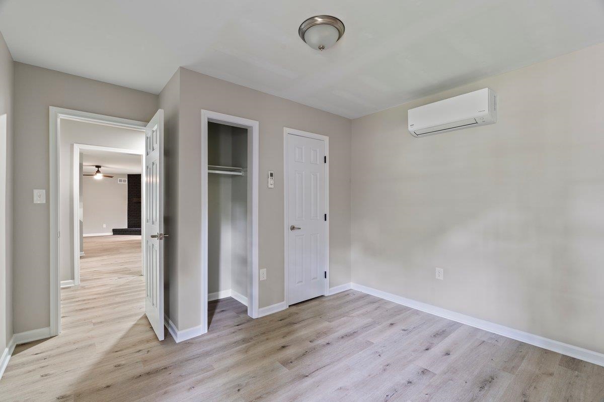 6410 Coteswood Road Memphis, TN 38134 - Photo 13 of 25 Unfurnished bedroom featuring a wall mounted air conditioner, light wood-style flooring, baseboards, and a closet