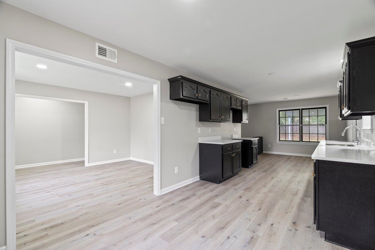 6410 Coteswood Road Memphis, TN 38134 - Photo 7 of 25 Kitchen with a sink, light wood-style floors, light countertops, baseboards, and dark cabinets