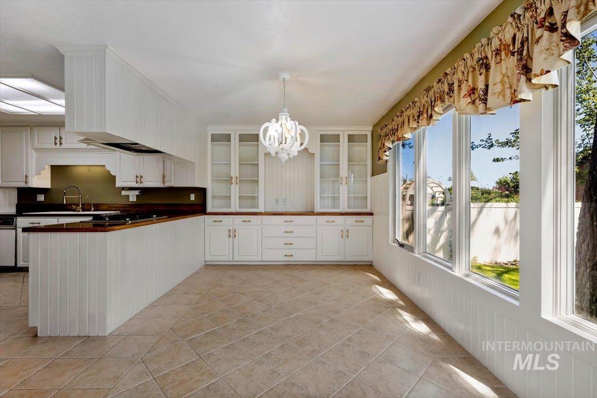 813 7th Street Rupert, ID 83350 - Photo 23 of 48 Eat-in kitchen featuring extensive white cabinetry, wood-finish countertops, and a white decorative chandelier