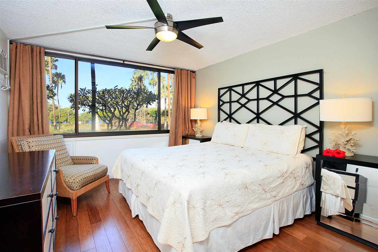 2695 South Kihei Road, Unit 10115 Kihei, HI 96753 - Photo 12 of 28 a bedroom with a bed a dresser and a large window