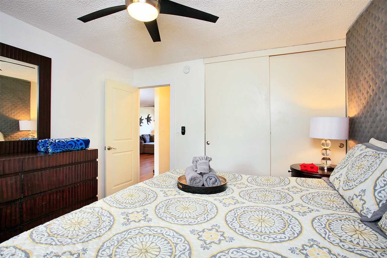 2695 South Kihei Road, Unit 10115 Kihei, HI 96753 - Photo 15 of 28 a bedroom with a bed and a chandelier