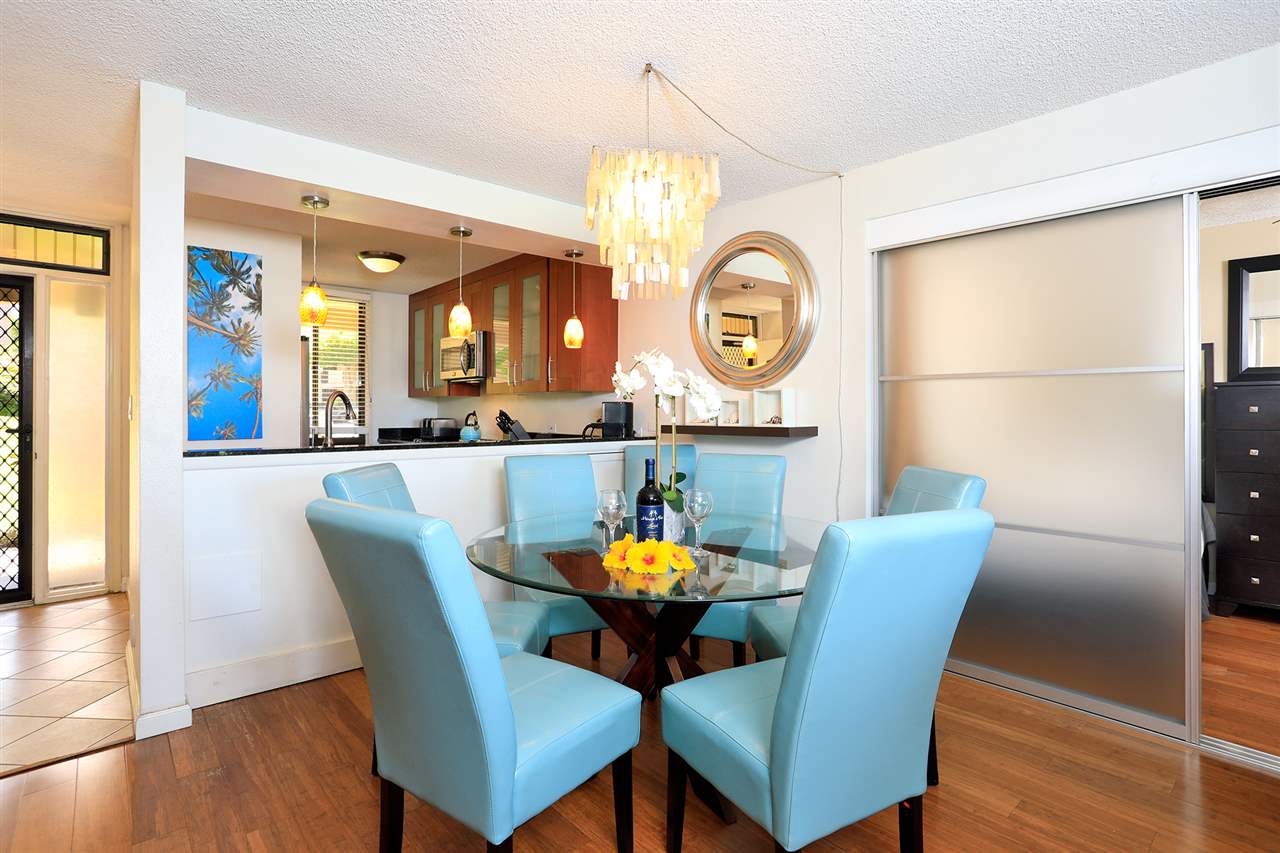 2695 South Kihei Road, Unit 10115 Kihei, HI 96753 - Photo 6 of 28 a dining room with furniture a potted plant and a chandelier