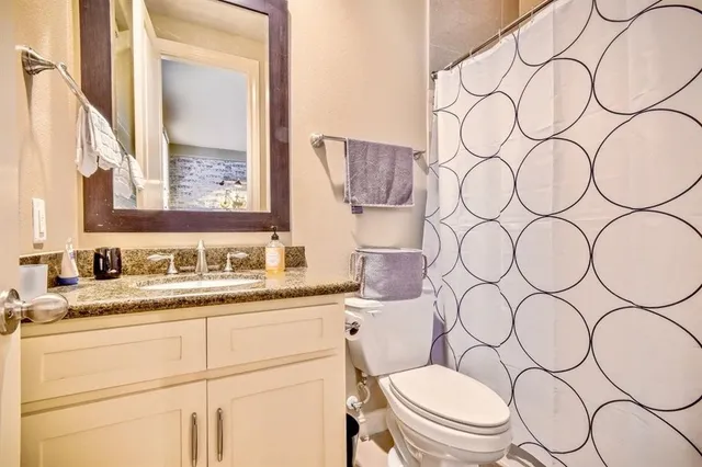 a bathroom with a granite countertop sink and a mirror with toilet