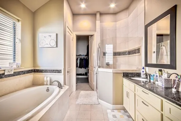 a bathroom with a granite countertop tub sink and mirror