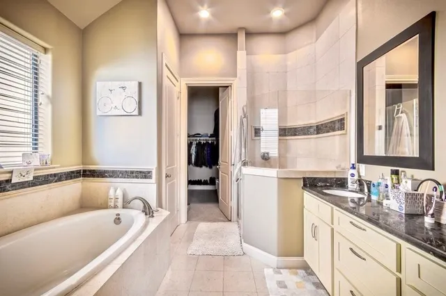 a bathroom with a granite countertop tub sink and mirror