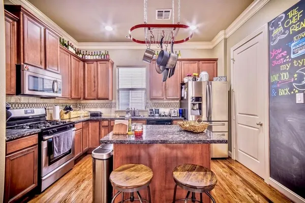 a kitchen with stainless steel appliances granite countertop a stove a sink dishwasher and cabinets with wooden floor