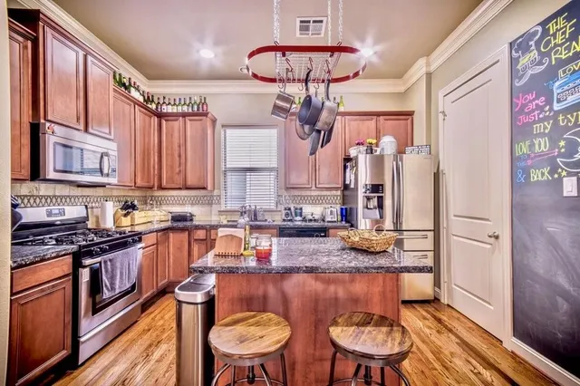 a kitchen with stainless steel appliances granite countertop a stove a sink dishwasher and cabinets with wooden floor