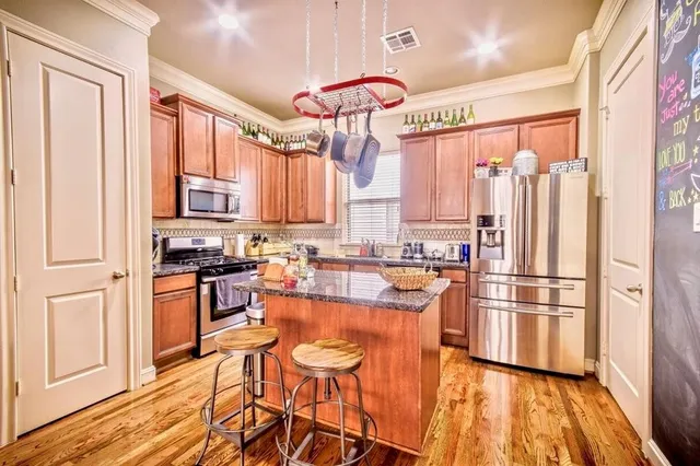 a kitchen with stainless steel appliances granite countertop a refrigerator a stove top oven and a sink