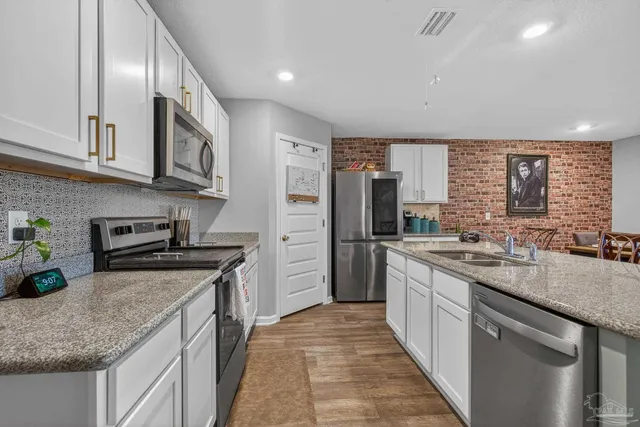 a dining hall with stainless steel appliances granite countertop a sink a stove a dining table and chairs with wooden floor