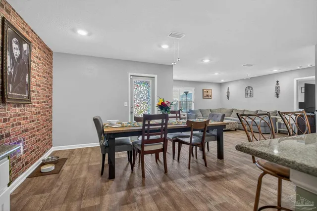 a dining area with stainless steel appliances a dining table chairs and a refrigerator