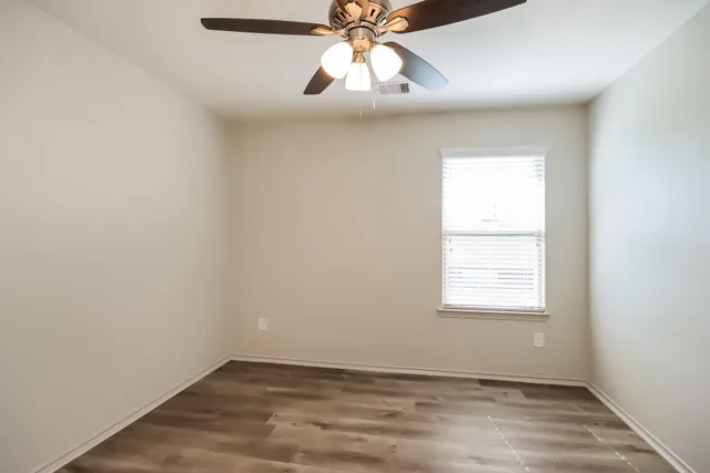an empty room with ceiling fan and window