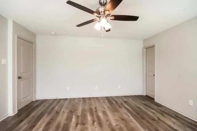 an empty room with windows and fan