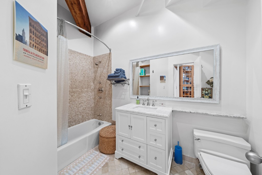 165 Duane Street, Unit 6A Manhattan, NY 10013 - Photo 22 of 29 a bathroom with a granite countertop toilet a sink a mirror a bathtub and shower