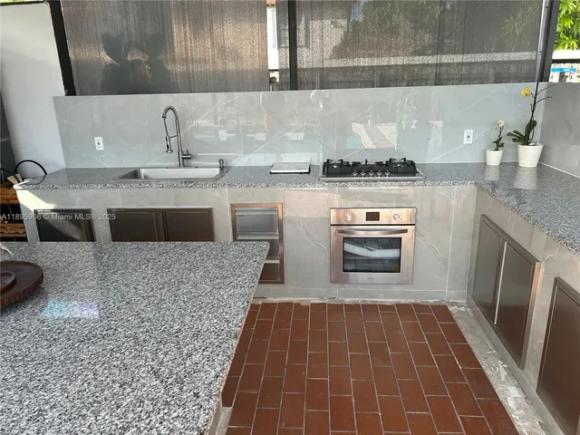 a kitchen with granite countertop a stove a sink and a microwave