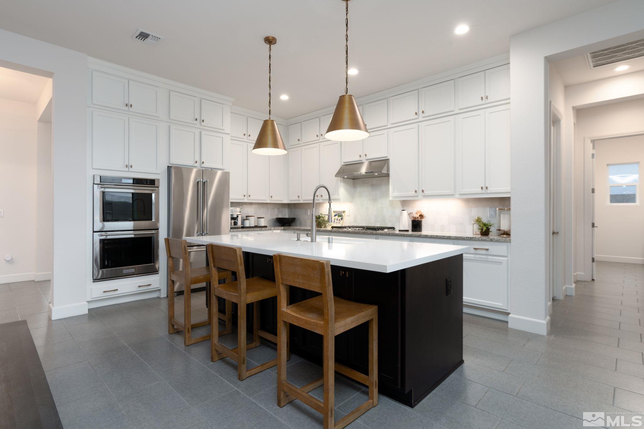 2343 Iron Square Drive Reno, NV 89521 - Photo 9 of 35 a kitchen with stainless steel appliances granite countertop a sink a stove a refrigerator and chairs
