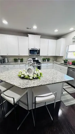 a kitchen with stainless steel appliances granite countertop a table chairs sink refrigerator and cabinets