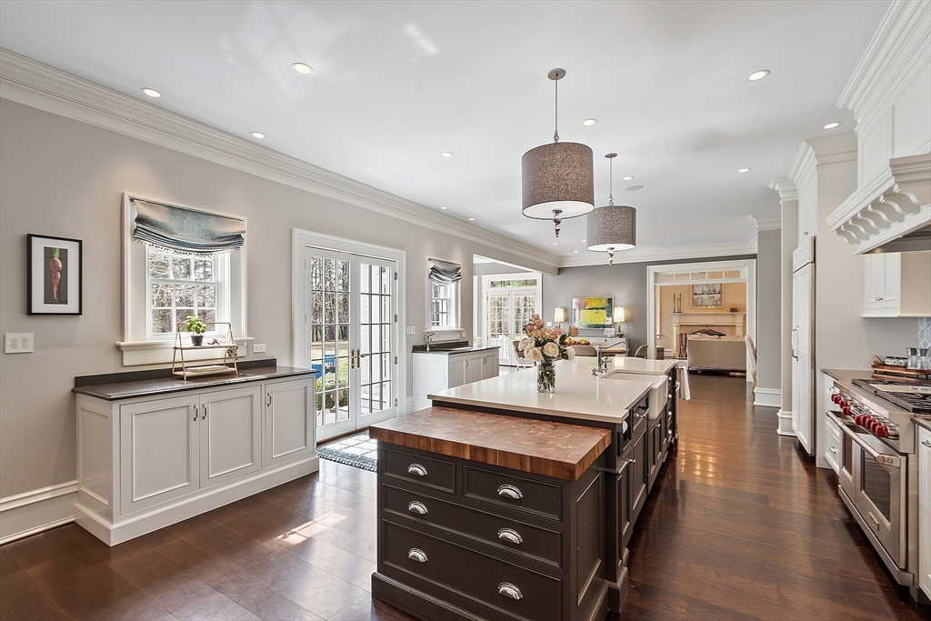 287 Westford Road Concord, MA 01742 - Photo 9 of 42 a large kitchen with kitchen island a stove a refrigerator a sink dishwasher a dining table and chairs with wooden floor