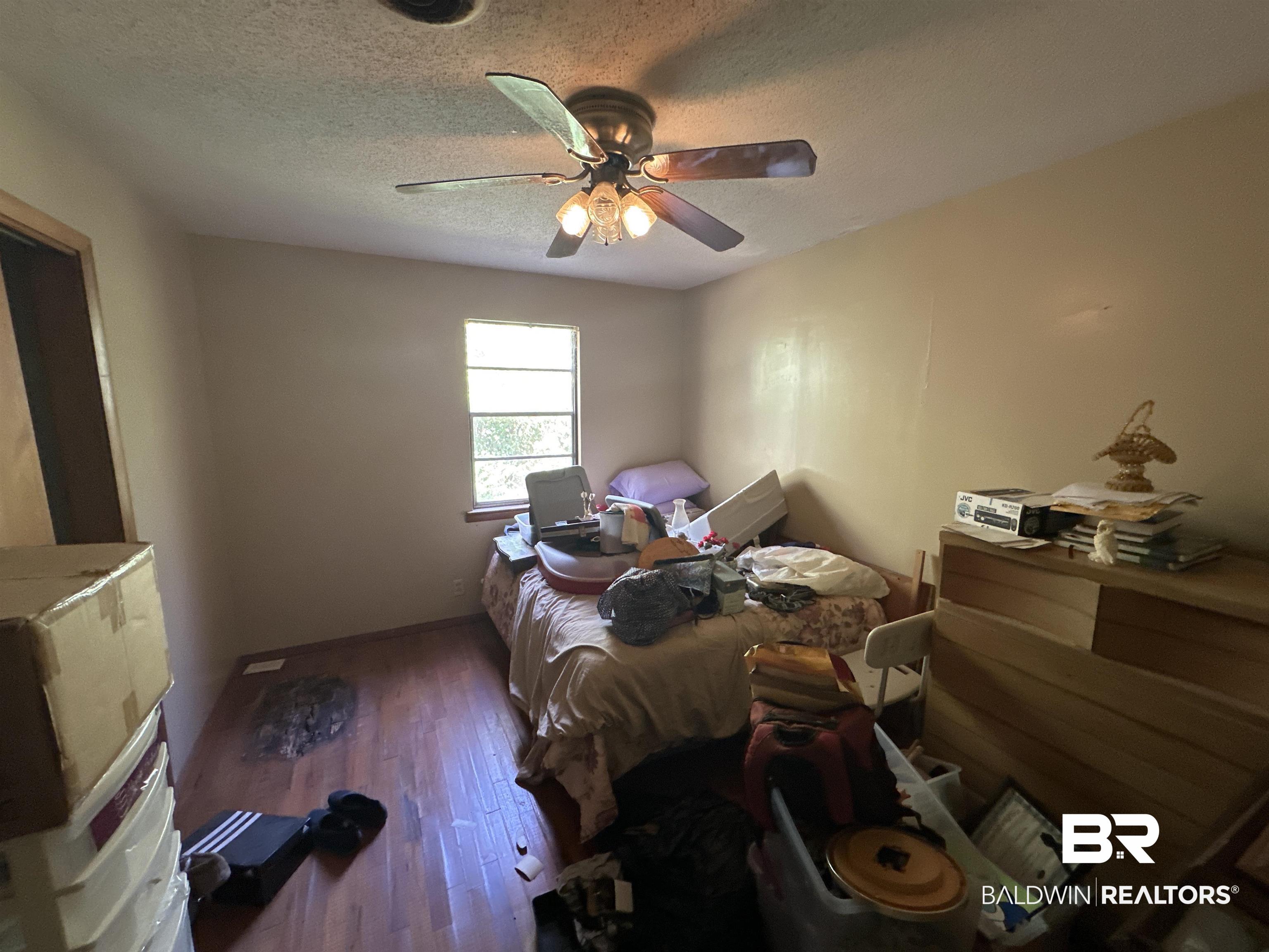 9520 C Four Mile Road Irvington, AL 36544 - Photo 21 of 32 Bedroom featuring ceiling fan, wood-type flooring, and a textured ceiling