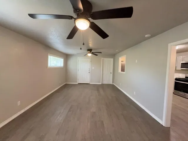 an empty room with ceiling fan and windows