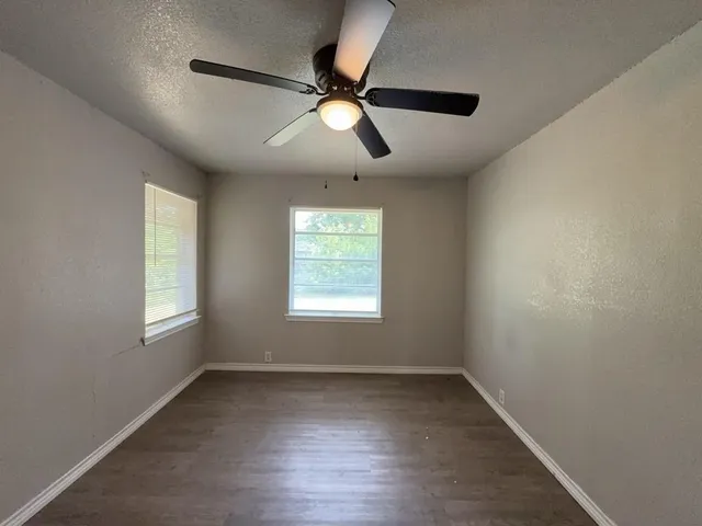 a view of empty room with wooden floor and fan