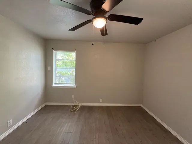 an empty room with a window and a fan