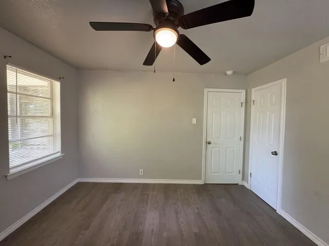 a view of an empty room with window and chandelier fan