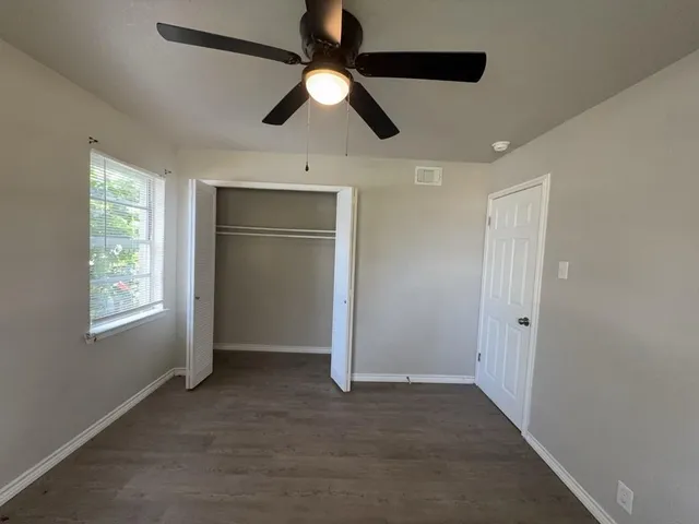 en empty room with windows and ceiling fan