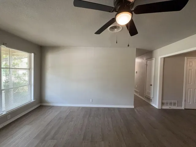 an empty room with wooden floor fan and window