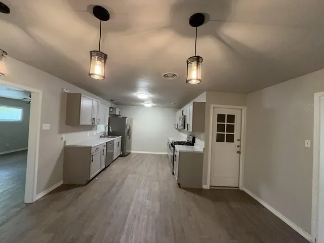 a view of a kitchen with a sink wooden floor and a refrigerator