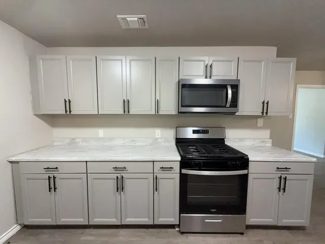 a kitchen with white cabinets stainless steel appliances and wooden cabinets