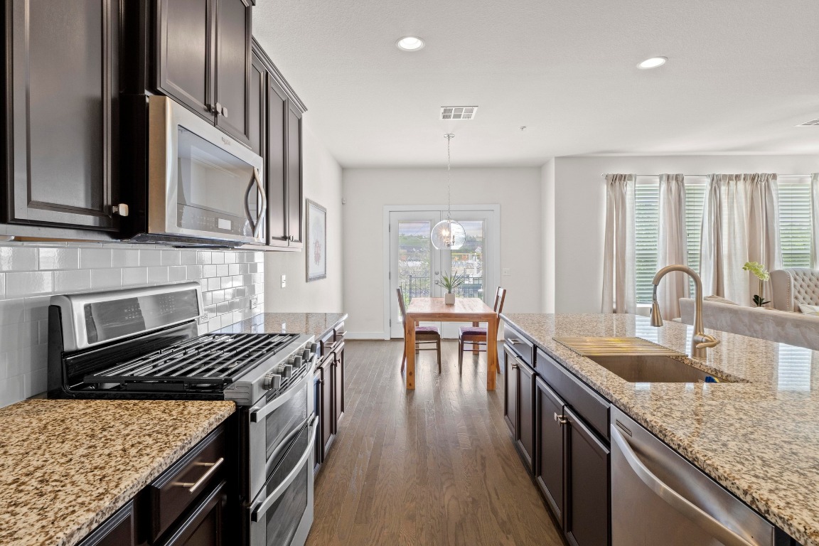 7407 Merrick Lane Austin, TX 78745 - Photo 11 of 34 a kitchen with granite countertop a stove top oven a sink a dining table and chairs