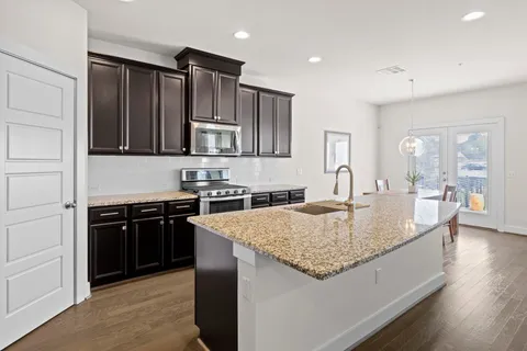 a kitchen with granite countertop kitchen island stainless steel appliances a sink stove and refrigerator