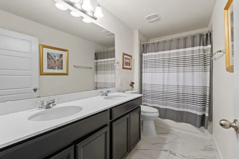 a bathroom with a double vanity sink toilet and shower
