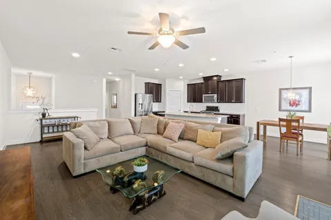 a living room with furniture kitchen view and a chandelier