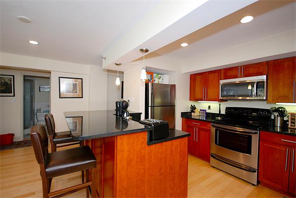 a kitchen with stainless steel appliances kitchen island granite countertop a refrigerator a stove a sink dishwasher a dining table and chairs with wooden floor