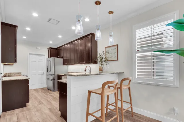 a kitchen with granite countertop a table chairs microwave and refrigerator