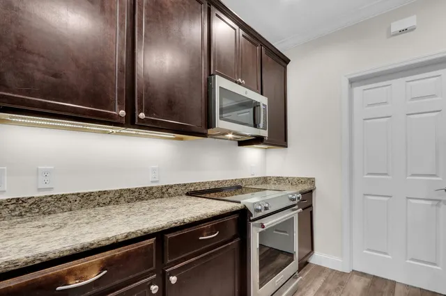 a view of a kitchen with stainless steel appliances granite countertop a stove and a microwave