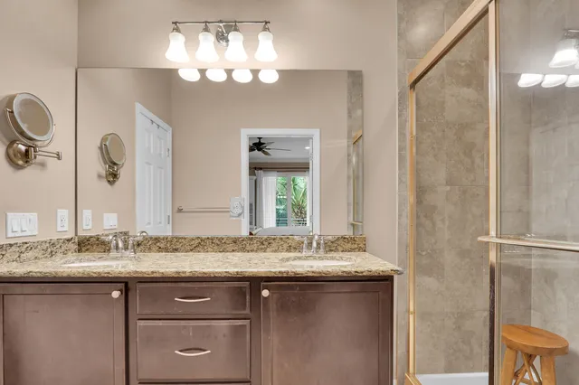 a bathroom with a granite countertop sink a large mirror and a shower